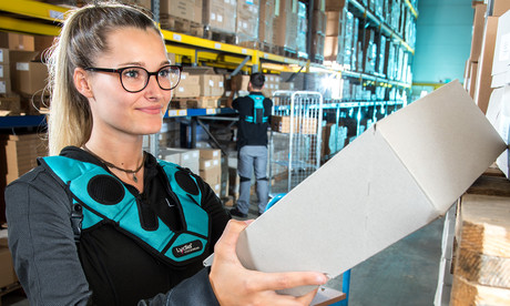 Female warehouse worker is picking with voice software Lydia Voice from the shelf and holding package in her hands.