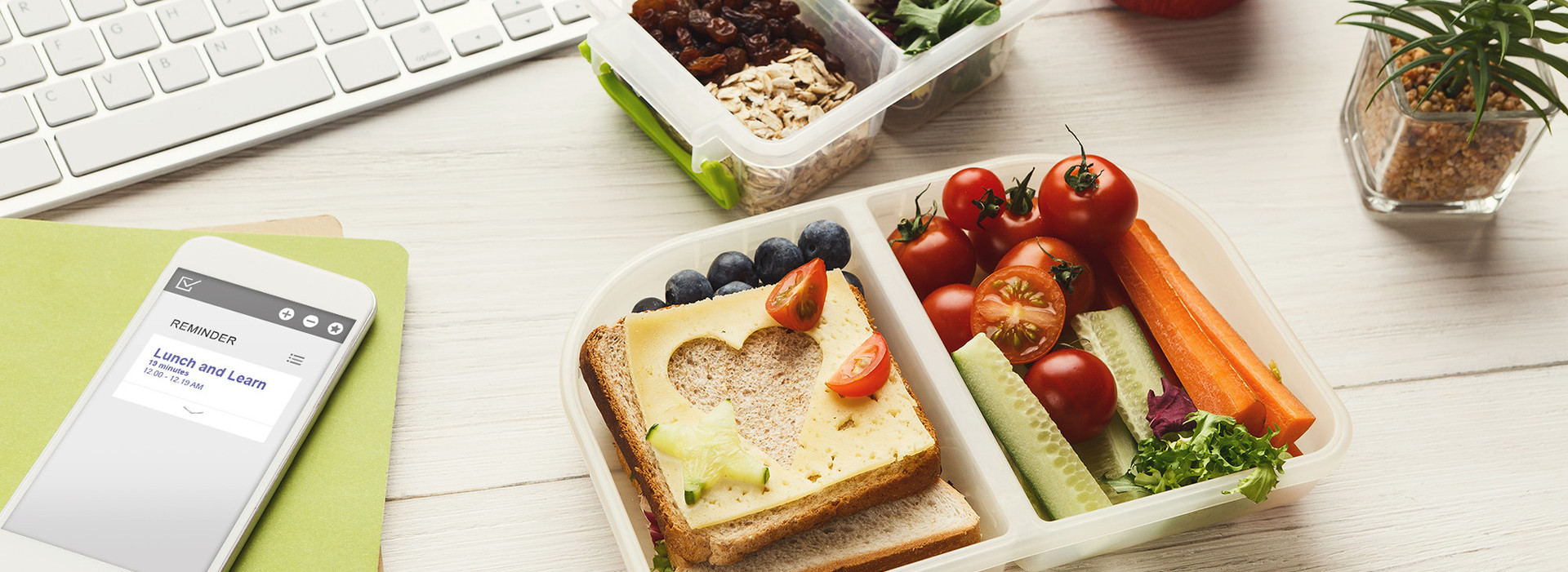 En la foto se puede ver una fiambrera con sándwiches y verduras y un teléfono móvil con la fecha del Lunch & Learn's de EPG