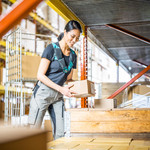 Female warehouse worker is picking with voice software Lydia Voice from the shelf and holding package in her hands.